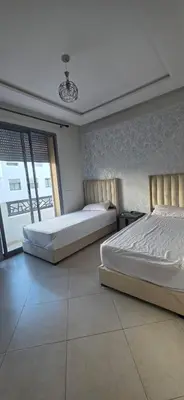 two beds in a large room with a window at appartement a louer sable d'or mansouria in Pont Blondin