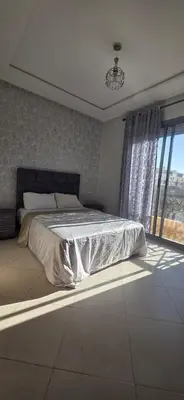 a bedroom with a bed and a large window at appartement a louer sable d'or mansouria in Pont Blondin