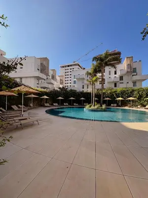 a swimming pool with tables and umbrellas and buildings at Smile City Homes in Casablanca