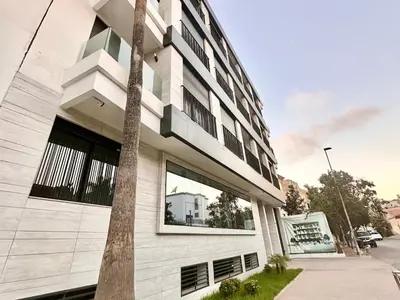 a white building with a palm tree in front of it at Calm Studio in Oasis, Near Train Station in Casablanca