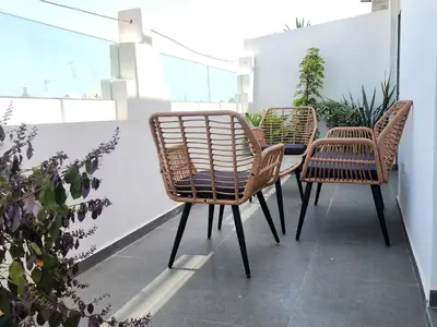 three rattan chairs and a table on a balcony at The Nineteen Racine by IB Signature - Stylish two-Bedroom flat - Wifi, Self Check-in, Day and Night Security, Terrace, free parking, close to all amenities in Casablanca