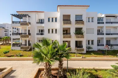 an apartment building with a palm tree in front of it at Seaside 3 bedrooms apartment in Mansouria near Sablette Beach Mohammadia in Pont Blondin