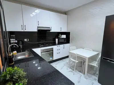 a kitchen with white cabinets and a sink and a table at Les Flots Blancs - Appartement détente et bonheur côté mer in Bouznika