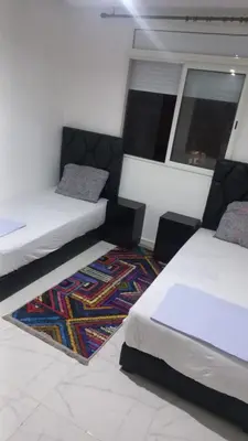 a bedroom with two beds and a rug at Appartement ville des roses in Mohammedia