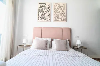 a white bedroom with a large bed with two lamps at Modern and cozy studio Close to CFC & Maarif in Casablanca