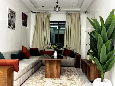 a living room with a couch and a table at Bel Appartement moderne et propre proche de l aéroport in Deroua