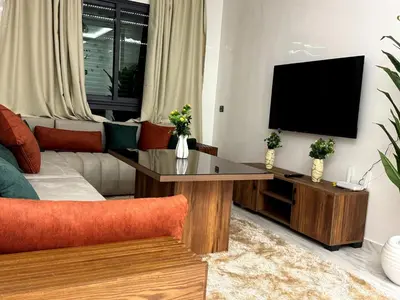 a living room with a couch and a flat screen tv at Bel Appartement moderne et propre proche de l aéroport in Deroua