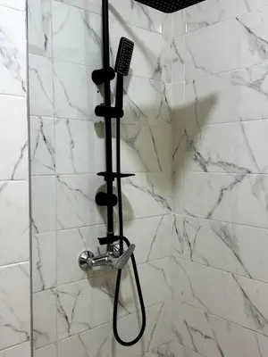 a shower with a black shower head at Bel Appartement moderne et propre proche de l aéroport in Deroua