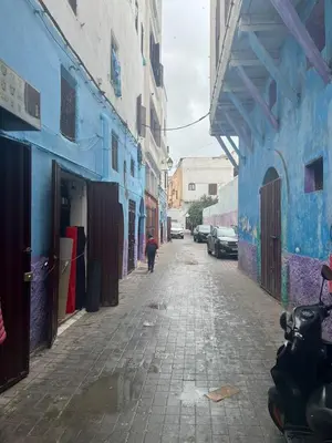 a person walking down a street with blue buildings at Hôte Nadia in Casablanca