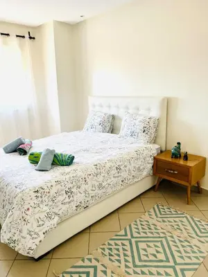 a bedroom with a white bed with a night stand at Cozy & family apartment in Mohammedia in Mohammedia