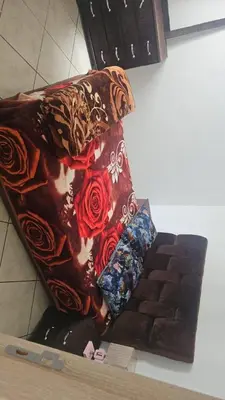 a blanket sitting on top of a chair with roses at Jolie appartement calme à louer par jour in Bouznika