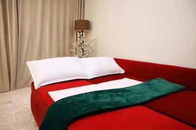 a red couch with a white and green blanket on it at R108- Gorgeous & Cosy Aprt with Wifi, Parking and Gym at the heart of Bourgogne in Casablanca-Port