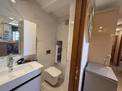 a white bathroom with a toilet and a sink at Apartement charmante amira in Oulad Kerroum