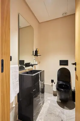 a bathroom with a black toilet and a mirror at Blue in Maarif