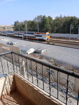 a train is traveling down the tracks next to a balcony at Appartement Design Prés du Stade My Abdellah in Temara