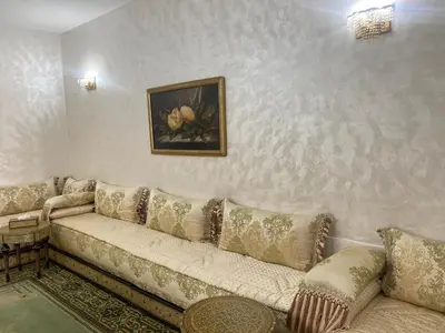 a living room with a couch and a painting on the wall at Tradition & Modernité in Rabat