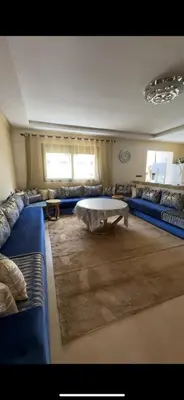 a living room with blue couches and a coffee table at Appartement de haut standing à EL MANSOURIA residence EBLA in Pont Blondin