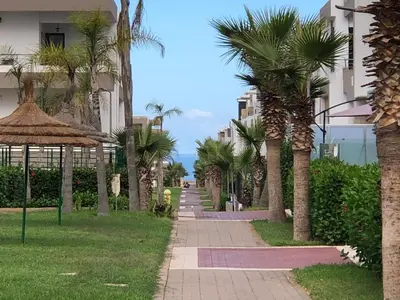 a walkway with palm trees in front of a building at Luxury Studio with Pool and Relaxing Atmosphere in O Ben Slimane