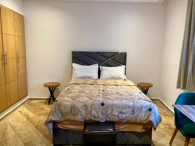a bedroom with a large bed with two chairs at Social apartment in Rabat