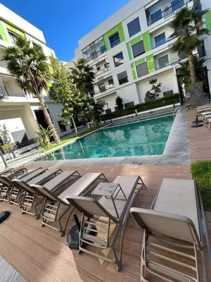 a pool with tables and chairs in front of a building at Résidence Natura Living in Mohammedia