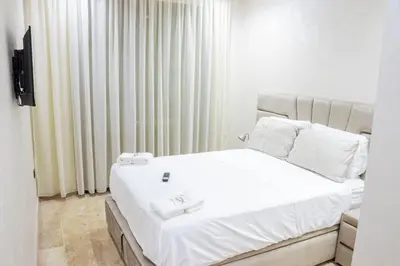 a bedroom with a white bed and a television at Dar Bouazza Luxury apartment with pools garden sports courts parking near the sea in Dar Bouazza