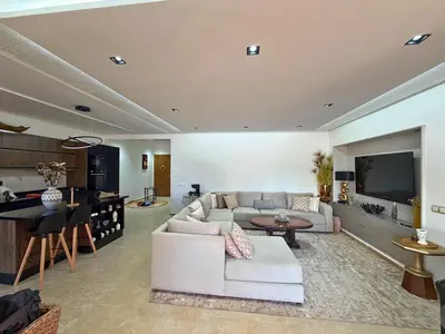 a living room with a white couch and a television at Appartement Premium 3 Chambres Piscine et Accès Plage Mansouria in O Ben Slimane