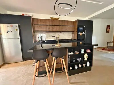 a kitchen with a counter with stools and a refrigerator at Appartement Premium 3 Chambres Piscine et Accès Plage Mansouria in O Ben Slimane
