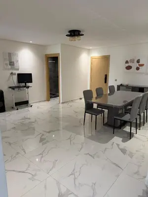 a dining room with a table and chairs on a marble floor at Superbe appartement 120 mc, Plage à pieds, 3 piscines & calme garanti - Sidi Rahal Plage in Sidi Rahal