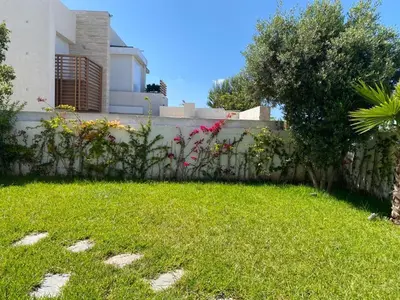 a backyard with a fence and a green yard at Villa de luxe CGI avec piscine in Bouskoura