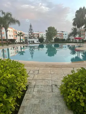 a large swimming pool with some trees and buildings at Bel appartement in O Ben Slimane