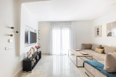 a white living room with a couch and a table at APGCI -Studio Élégant a 5 min du Stade Mohamed V in Casablanca