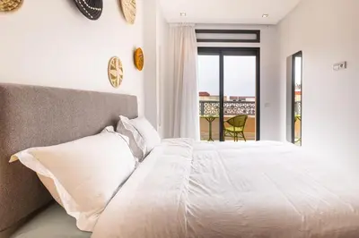 a bedroom with a white bed and a balcony at APGCI -Studio Élégant a 5 min du Stade Mohamed V in Casablanca