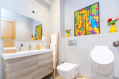a bathroom with a sink and a toilet and paintings at Luxury central Apartment - 3BR - Flipper - Parking in Casablanca