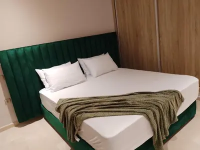 a bed with a green headboard and white pillows at Les belles loges in Bouskoura
