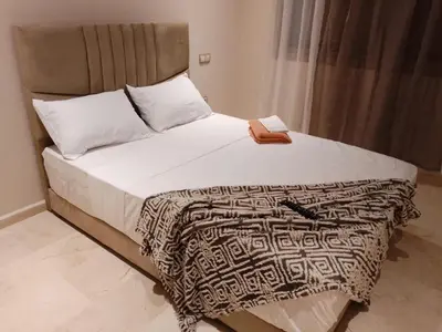 a bedroom with a large bed with white sheets and a book at Les belles loges in Bouskoura