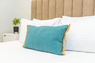 a blue pillow sitting on a bed with white pillows at Seafront 2BR AC Sunny Corniche in Casablanca