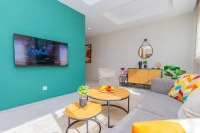 a living room with a couch and a tv on a wall at Seafront 2BR AC Sunny Corniche in Casablanca