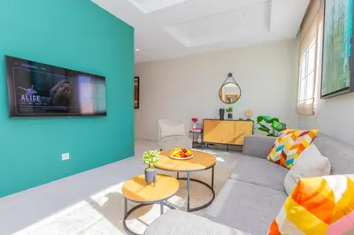 a living room with a couch and a tv on a wall at Seafront 2BR AC Sunny Corniche in Casablanca