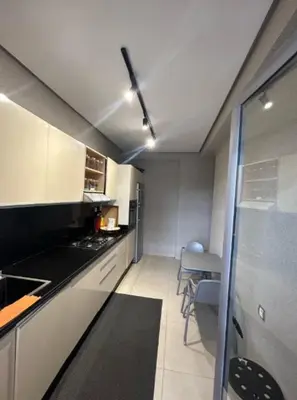a kitchen with white cabinets and a black counter top at Beach 1 min walk Pool Elevator Carrefour in O Ben Slimane