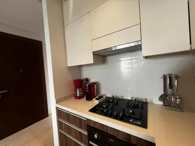 a kitchen with a stove top and white cabinets at Modern 1BR Orangeraie - Terrace & Pool in Rabat