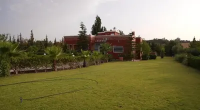 a red house with a basketball court in a yard at Le refuge vert in Berrechid