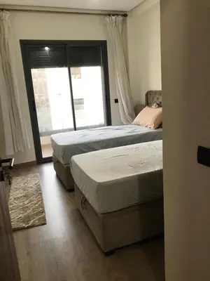 two beds in a bedroom with a large window at appartement in Mohammedia