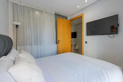 a bedroom with a white bed and a flat screen tv at Faya Nova- Appart hotel Central Stay in Casablanca