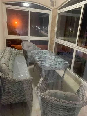 a living room with a table and chairs and windows at Lovely three sides Appart in Ola Blanca in Sidi Rahal