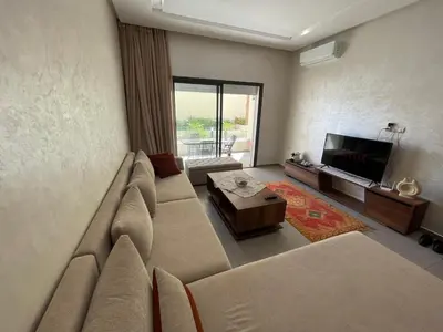 a living room with a large couch and a television at Cozy Studio with pool, fiber optics in Mansouria
