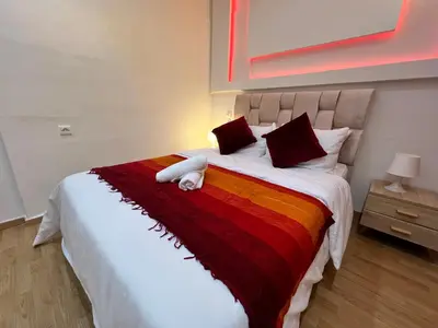 a bedroom with a large bed with a colorful blanket at Cosy apartment steps from shore & public transport in Rabat