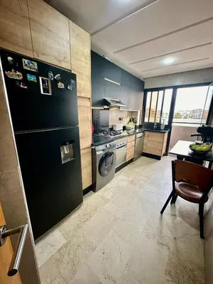 a kitchen with a refrigerator and a table with a chair at Twin Center View Apt in Maarif in Maarif