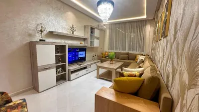 a living room with a couch and a tv at Appartement chic Dahomey plage - Rabat & Bouznika, mer et culture in Bouznika