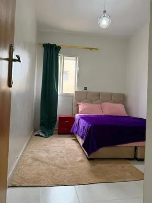 a bedroom with a bed with purple sheets and a window at Résidence Haja in Casablanca