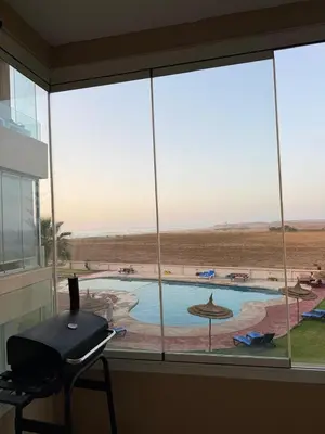 a view of a swimming pool from a window at Evasion apartment with beach and pool views in Bouznika